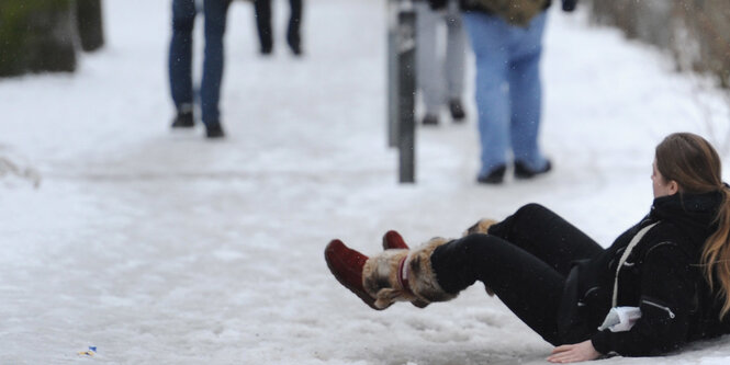 EIne Frau sitzt auf schneeglattem Fußboden