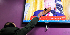 Ein Mann haut mit einem Schuh auf das Fernsehbild von Us-Präsident Trump.