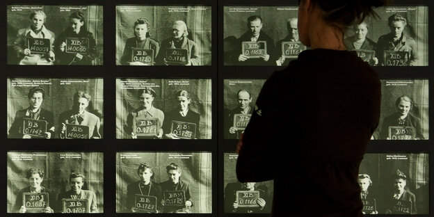 Eine Besucherin betrachtet in der KZ-Gedenkstätte Bergen-Belsen Registrierungsfotos polnischer Kriegsgefangener aus dem Warschauer Aufstand.