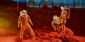 Drei Astronauten auf rotem Gestein auf einer Theaterbühne.