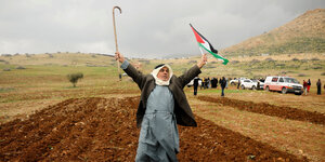 Ein Demonstant steht mit einer Palästinensischne Flagge auf einem Acker