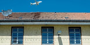 Abschiebungsgefängnis Langenhagen: Ein gelber Bau mit Gittern vor den Fenstern, im Hintergrund ein Flugzeug