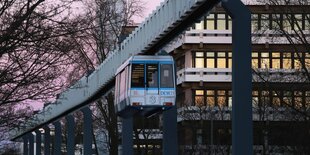 Eine Hoch-Bahn fährt an einem Haus vorbei.