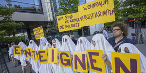 Demo von Deutsche Wohnen und Co. enteignen: Als Gespenster verkleidete Aktivist:innen demonstrieren vor einer Versammlung der Deutschen Wohnen