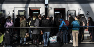 Viele Menschen drängen sich auf einem Bahnsteig vor einem Zug