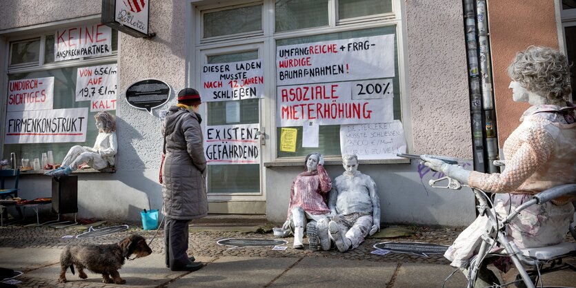 Lebensechte Puppen sitzen vor einem geschlossenen Geschäft