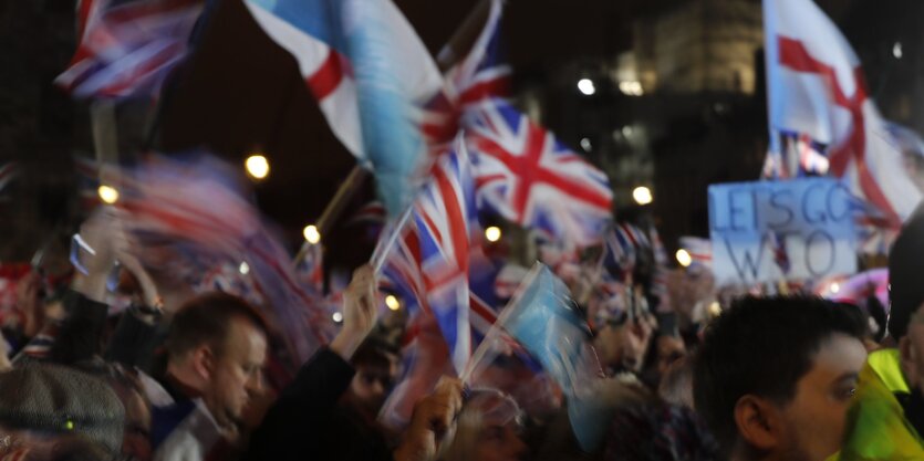 Zahlreiche Menschen schwenken in der Dunkelheit Union Jacks.