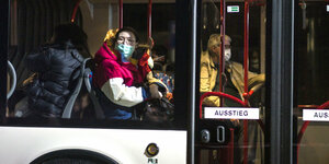 Menschen mit Mundschutz sitzen in enem Bus