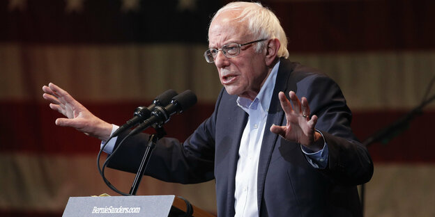 US-Politiker Bernie Sanders steht mit ausgebreiteten Armen am Rednerpult bei seiner Wahlkampagne
