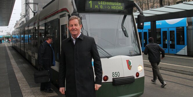 Man sieht eine Bushaltestelle, einen Bus und einen Mann davor