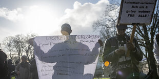 Zwei junge Männer halten auf der Demo von "Together we are Bremen" ein Plakat mit ihren Forderungen für Geflüchtete hoch. Eine davon: Keine Kriminalisierung von Minderjährigen