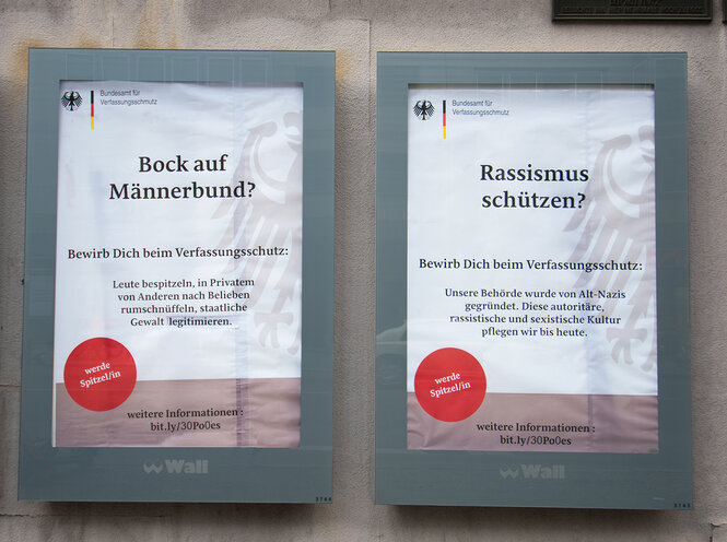 Adbusting-Aktion gegen Geheimdienst: Zwei Plakate hängen in Kästen der Wall AG