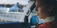 Eine junge Frau sitzt auf dem Beifahrersitz eines Autos.