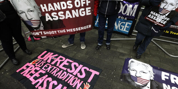 Protest Plakate mit Assange Portraits auf dem Boden