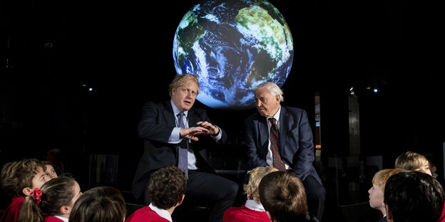 Johnson und Attenborough im Gespräch, vorne zuhörende SchülerInnen