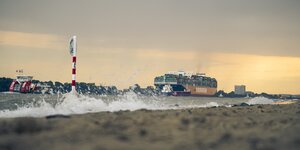 Containerschiff auf der Elbe, im Vordergrund schwappt Wasser