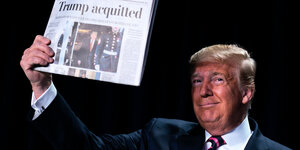 Trump hält eine Zeitung hoch