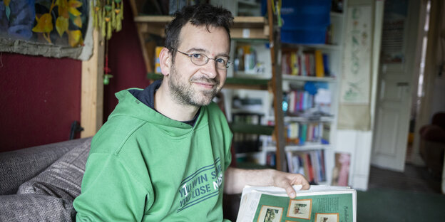 Dirko Goebel sitztauf einem Sofa und trägt einen grünen Pulli