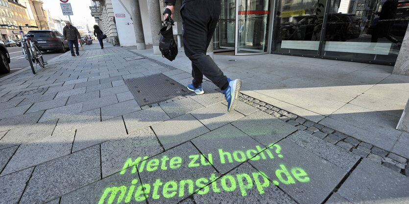 Ine mann läuft die Strasse entlang. Auf dem Boden steht Miete zu hoch mietenstopp.de