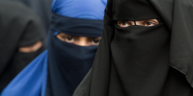 Drei Frauen, deren Gesichter von Niqabs verdeckt werden. Nur die Augen sind frei