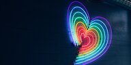 Ein regenbogenfarbenes Herz leuchtet an eienr Wand