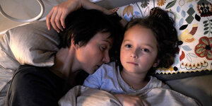 Szene aus einem Film: Frau kuschelt mit kleinem Kind im Bett
