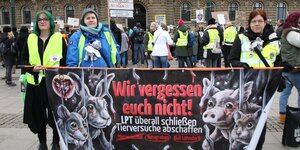 Demonstrierende in Gelbwesten halten ein Banner mit der Aufschrift "Wir vergessen euch nicht" und Zeichungen von Tieren.