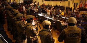 Bewaffnete Soldaten stehen in einem Sitzungssaal