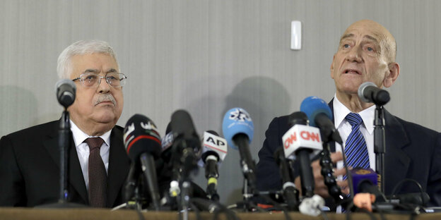 Mahmud Abbas und Ehud Olmert sitzen vor zahlreichen Mikrofonen