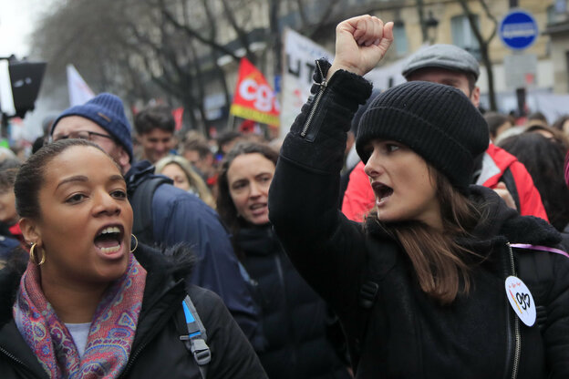 Zwei Frauen auf einer Demonstration skandieren, eine hebt die Faust
