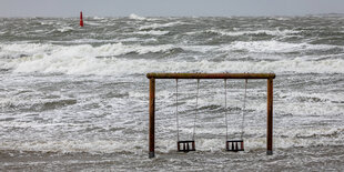 Eine Kinderschaukel steht am Strand von Norderney unter Wasser.