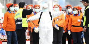 MitarbeiterInnen des Gesundheitswesens in Taiwan bereiten sich in einem Spezialanzug auf einen Einsatz vor.