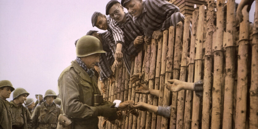 US-Soldaten verteilen Zigaretten an Gefangene des KZ Dachau bei der Befreiung.