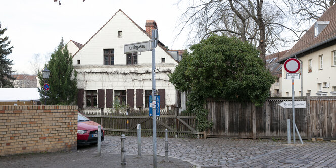 Die Kirchgasse: Ein weißes Haus neben einem Baum, parkendes Auto.