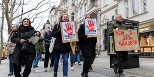 Mieter-Demo am Kurfürstendamm: Mieter:innen laufen mit Transparenten über einen breiten Bürgersteig: Kein Monopoly mit unseren Häusern steht auf einem Plakat. Eine ältere Demonstranting schlägt mit einem Holzllöffel auf einen Kochtopf