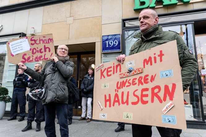 Demo von Kotti & Co am Kudamm: Polizisten stehen vor der Nummer 199, demonstrierende Mieter:innen stehen davor und halten selbstgemachte Plakate