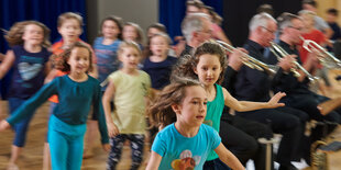 Kinder tanzen um ein Orchester herum