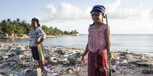 Frauen neben angeschwemmtem Plastikmüll auf Kiribati