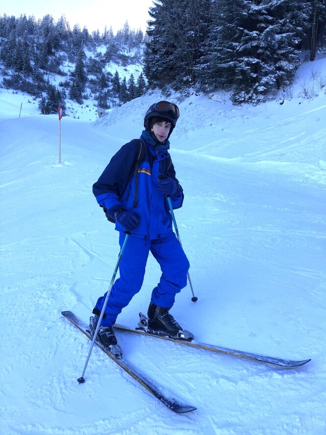 Ein Mann auf Skiern im blauen Skianzug posiert auf Skipiste