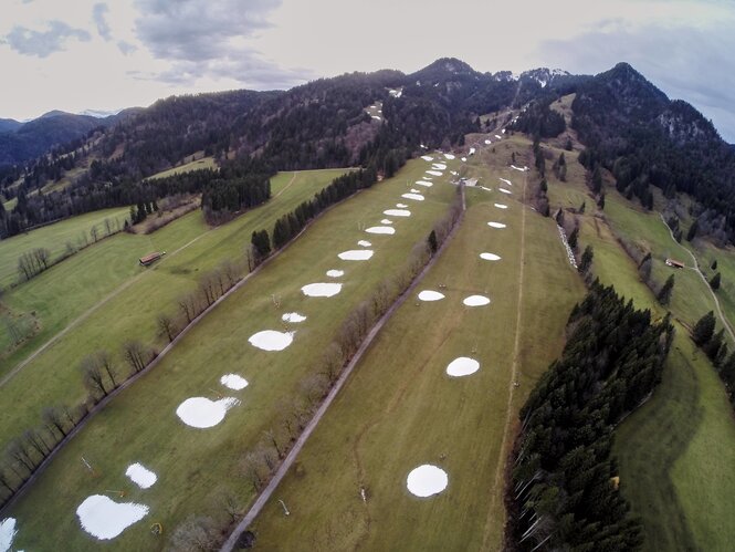 Eine Piste mit grünem Gras und nur vereinzlten Schneeflecken darauf