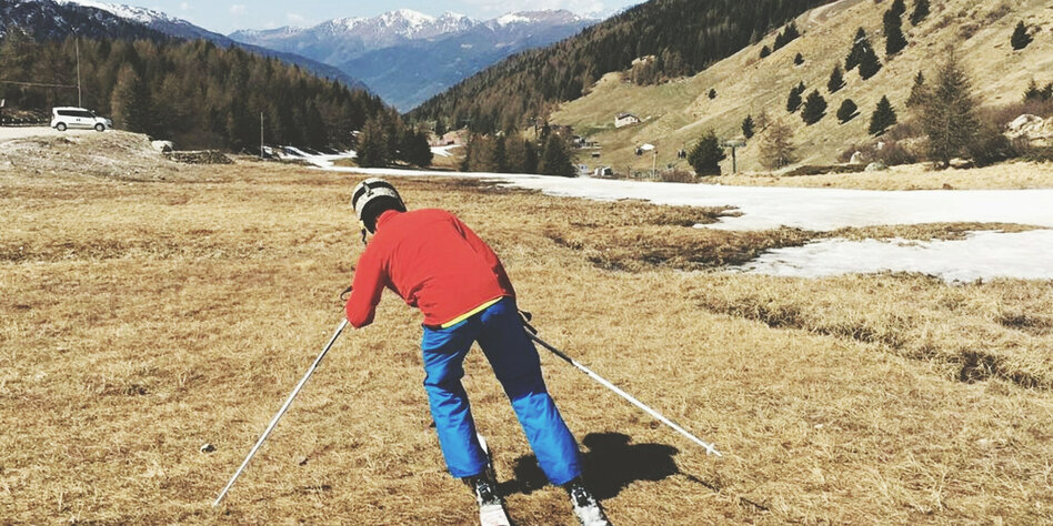 Skifahrer auf einem Hang ohne Schnee.