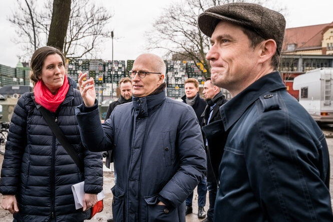 Tschentscher steht gestikulierend zwischen Leuten