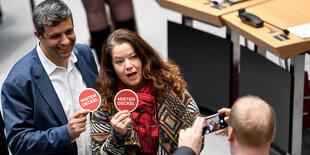 Zwei Abgeordnete halten ein Schild in eine Handykamera