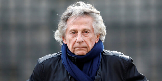 Filmregisseur Roman Polanski in schwarzer Lederjacke und blauem Schal.