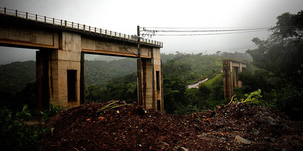 eine in der Mitte zerstörte Brücke im Urwald bei Regenwetter