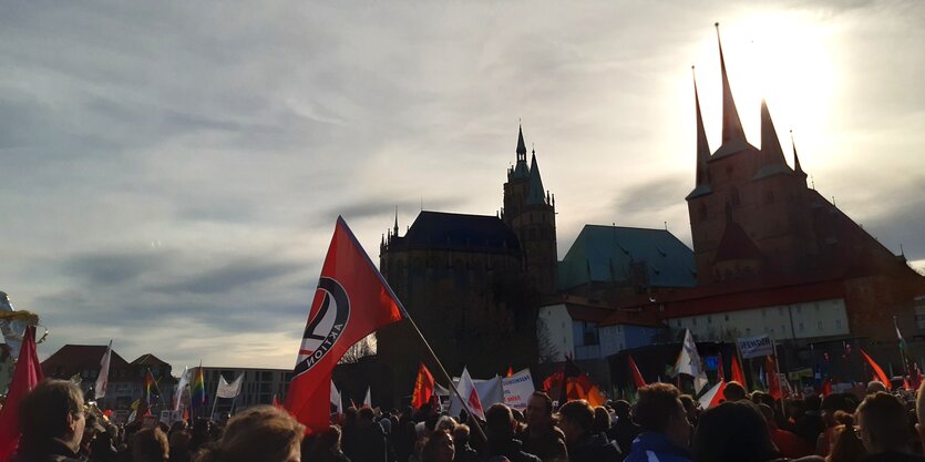 Viele Demonstrierende vor einer Kirche, dahinter die Sonne