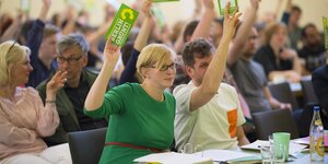 Auf eine Landesdelegiertenkonferenz der Berliner Grünen wird über einen Antrag abgestimmt - viele Hände mit Abstimmkarten gehem in die Luft