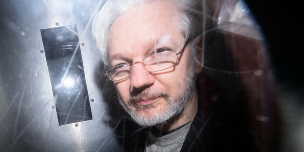 Wikileaks-Gründer Julian Assange wird im britischen Gericht von einem Fotografen abgefangen. Assange trägt einen weiß-grauen Vollbart und Brille