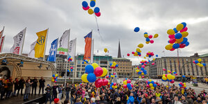 Menschen lassen farbige Luftballons in den grauen Himmel steigen