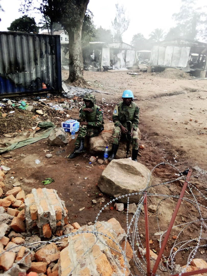 UN-Soldaten sitzen in einem zerstörten Lager.